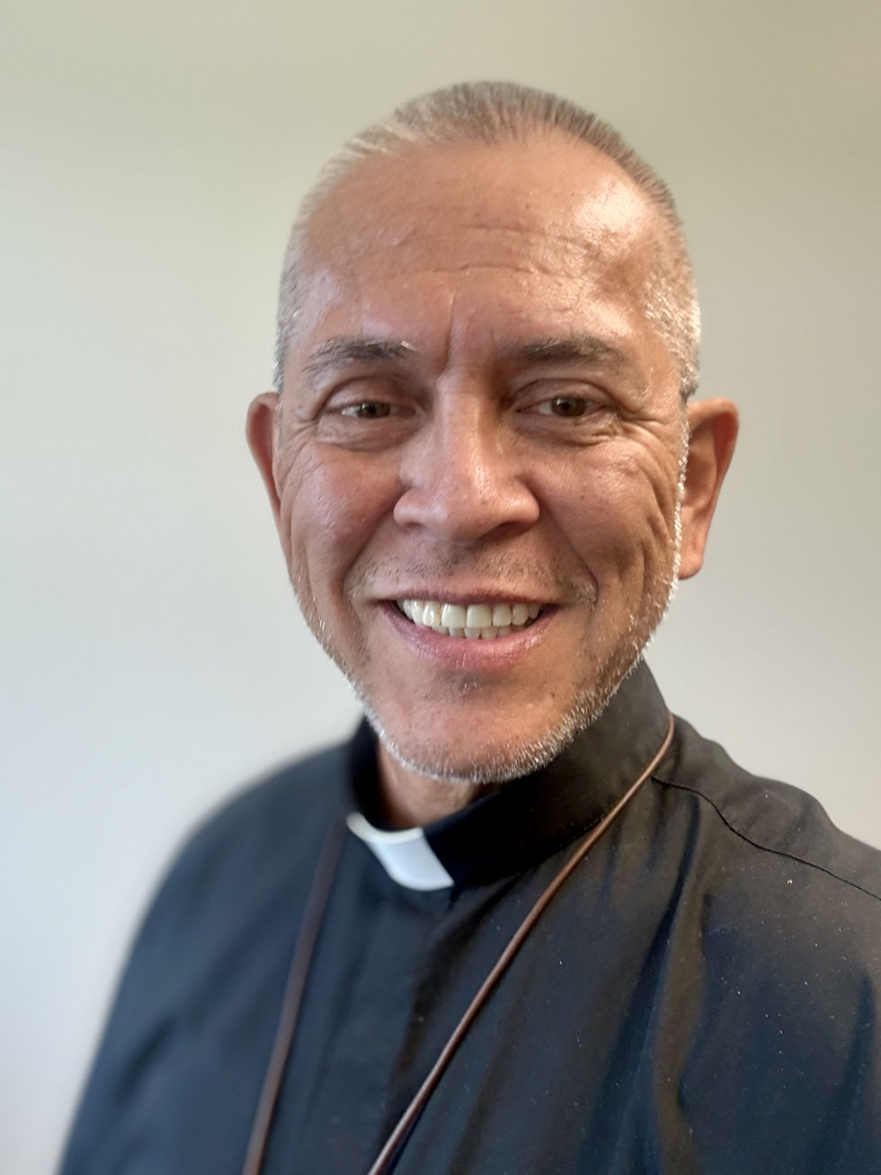 A priest in a green cassock smiling