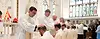 A line of priests blessing other priests kneeling in front of them with their hands on their heads