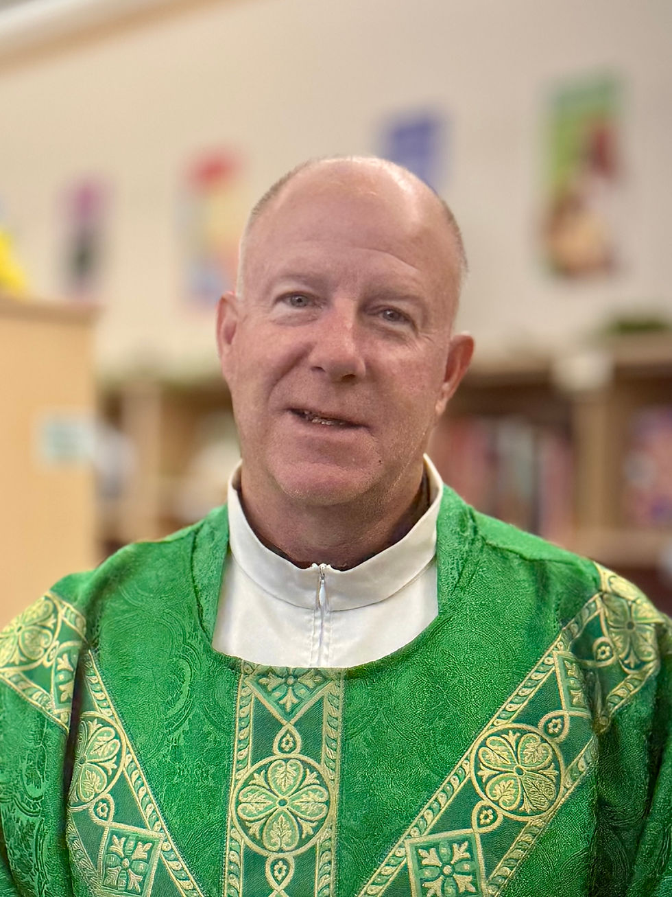 A priest in a green cassock smiling